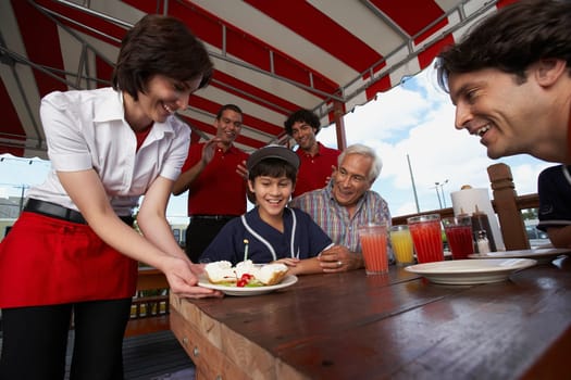 Boy celebrating his birthday with his father and grandfather in a restaurant