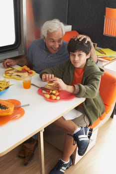 Senior man with his grandson having meal at the dining table