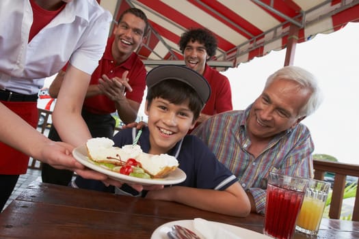 Portrait of a boy celebrating his birthday with his grandfather in a restaurant