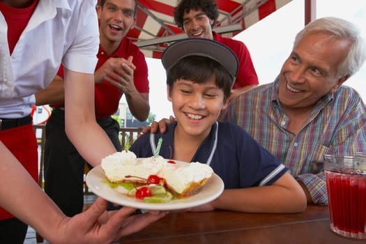 Boy celebrating his birthday with his grandfather in a restaurant