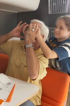 Girl covering her grandfather's eyes from behind