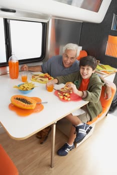 Senior man with his grandson having meal at the dining table