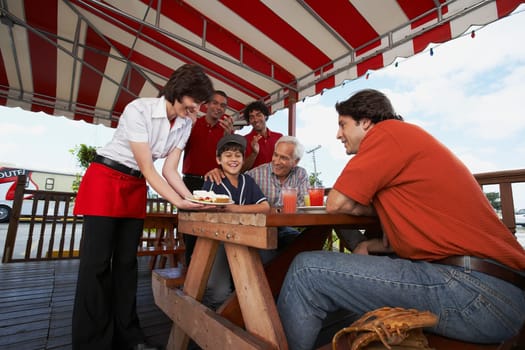 Boy celebrating his birthday with his father and grandfather in a restaurant