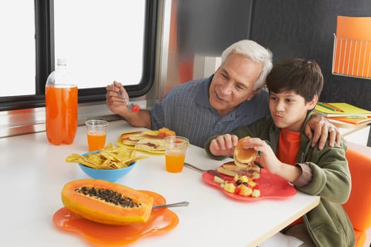 Senior man with his grandson having meal at the dining table