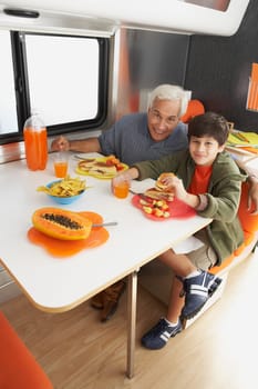 Senior man with his grandson having meal at the dining table