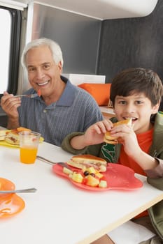 Senior man with his grandson having meal at the dining table