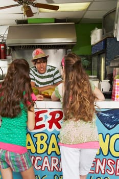 Rear view of two teenage girls talking to a bartender in a juice bar