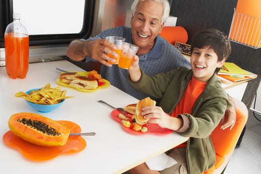 Portrait of a boy with his grandfather toasting glasses of juice