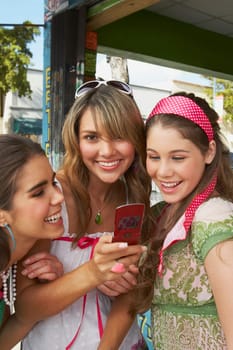 Close-up of a teenage girl holding a mobile phone and smiling with her friends