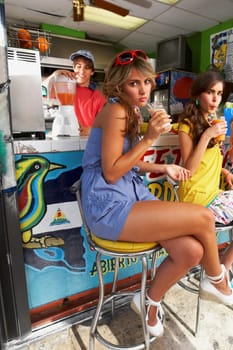 Close-up of a teenage girl drinking juice with a young woman