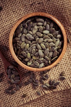 Organic pumpkin seeds in bowl on wooden background