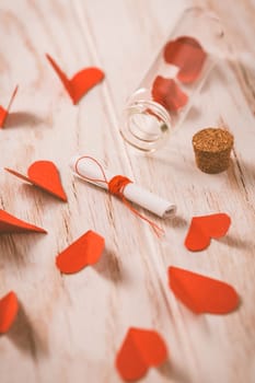 Love message in a bottle with paper hearts on wooden background -happy Valentine