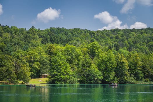Tourists paddling in two paddleboats on emerald green lake in Plitvice Lakes National Park UNESCO World Heritage in Croatia