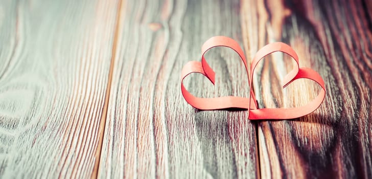Two paper hearts on wooden background in vintage look - soft focus. Symbol of love. Space for text.