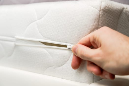 Hand opening cover of new mattress with zipper. Changing and washing cover. Front view. Close up