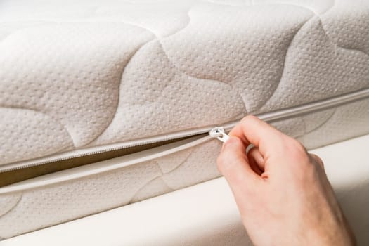 Hand opening cover of new mattress with zipper. Changing and washing cover. Front view. Close up