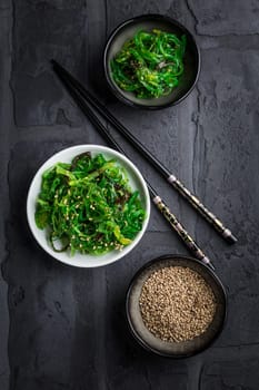 Traditional Japanese wakame salad with sesame seeds on black background. Healthy and fresh seaweed salad.