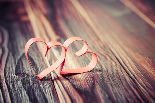 Two paper hearts on wooden background in vintage look - soft focus. Symbol of love. Space for text.
