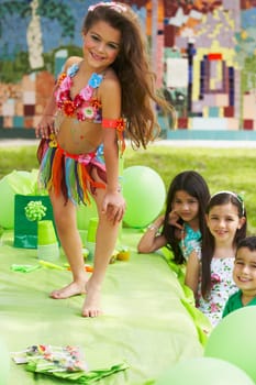 Girl dancing on a table at a birthday party with her three friends beside her