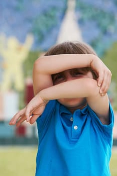 Portrait of a boy hiding his face with his arms