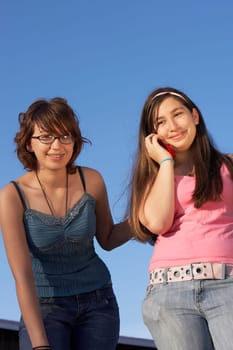 Portrait of a teenage girl smiling and her sister talking on a mobile phone