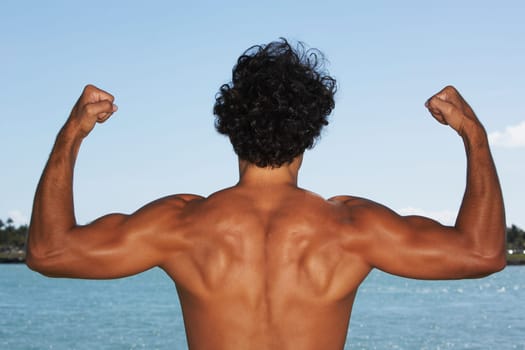 Rear view of a young man flexing his muscles