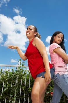 Side profile of two teenage girls standing back to back