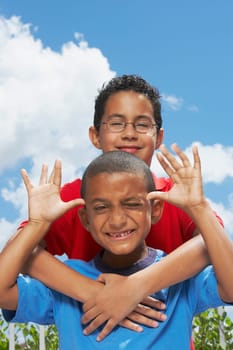 Close-up of a boy making a face with his friend hugging him from behind