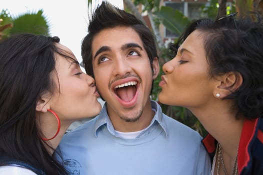 Close-up of two young women kissing a young man