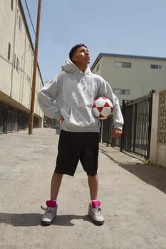 Young man standing on the street holding a soccer ball