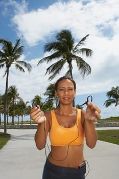 Portrait of a mature woman offering her ear bud, Miami beach, Florida, USA