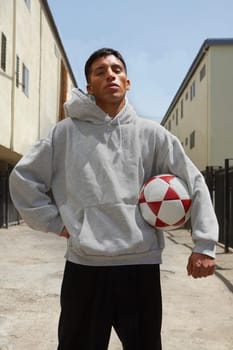 Young man standing on the street holding a soccer ball