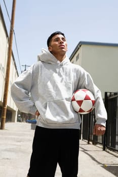 Young man standing on the street holding a soccer ball