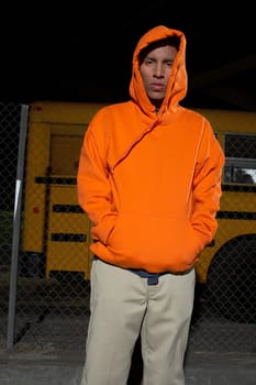 Portrait of a young man standing with his hands in his pockets and looking serious