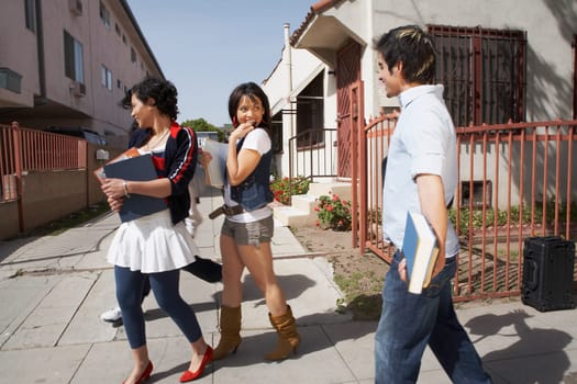 Side profile of three college students walking together on the street