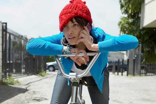 Close-up of a young woman sitting on a bicycle and talking on a mobile phone