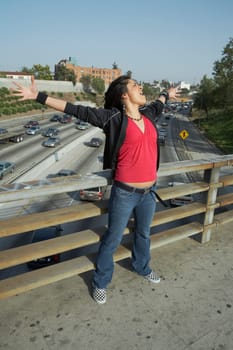 Young woman standing on an overpass with her arms outstretched
