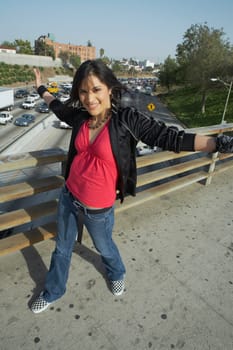 Portrait of a young woman walking on an overpass with her arms outstretched