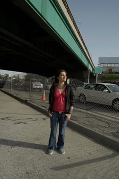 Young woman standing under an overpass with her hands in her pockets
