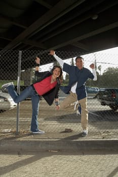 Portrait of a young couple gesturing in front of a chain-link fence