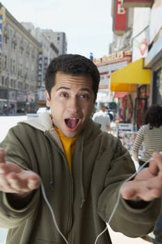 Portrait of a young man offering an ear bud to listen music