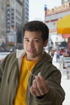 Portrait of a young man offering an ear bud to listen music