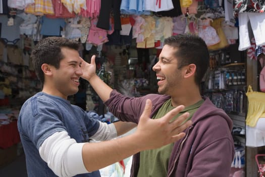 Close-up of two young men smiling in front of a clothing store