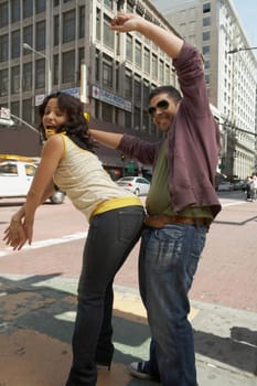 Side profile of a young couple reggaeton dancing on the road