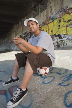Portrait of a young man sitting on a soccer ball and smiling