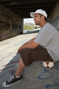 Side profile of a young man sitting on a soccer ball