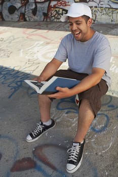 High angle view of a young man reading a book and laughing