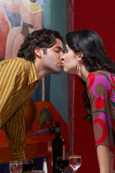 Side profile of a young couple kissing each other in a restaurant