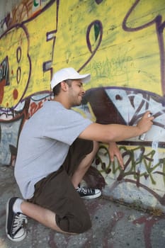 Side profile of a young man making a graffiti on a wall
