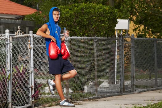 Side profile of a teenage boy listening an ipod and holding a bottle of water